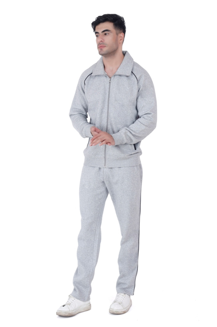 A man in Trufit’s Grey Grindle zip-up tracksuit with a wide collar and black piping, standing casually with hands clasped together, wearing white sneakers against a white background.